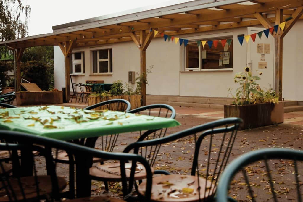 Emils Ecke Außenbereich Emils Ecke: Blick auf Tische und Stühle mit Herbstlaub, im Hintergrund das Gebäude